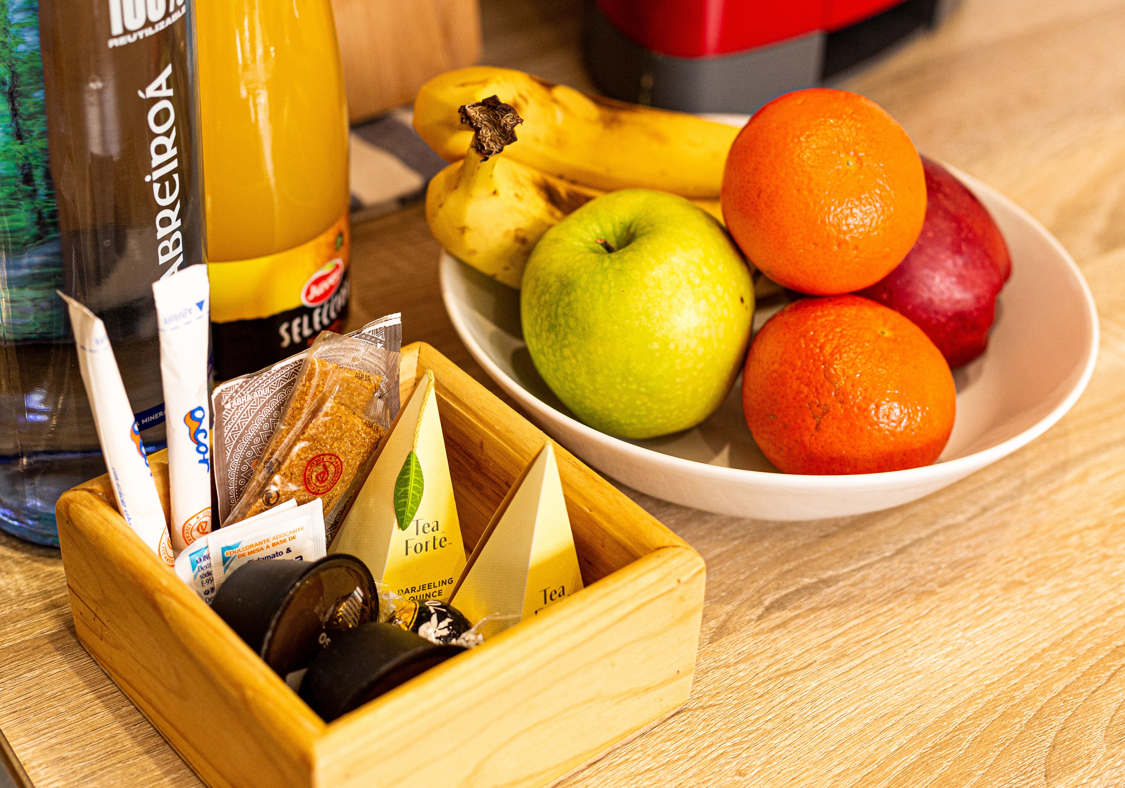 A wooden tray with tea bags and a bottle of orange juice.