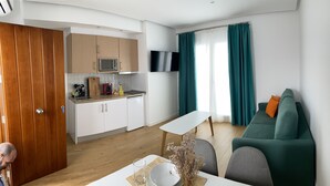 A compact living space with a kitchenette, a dining area, and a sofa.