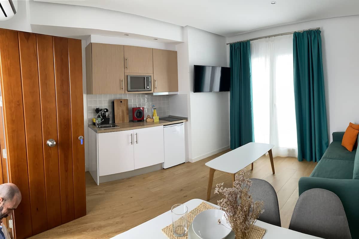 Een knus woongedeelte met een kitchenette, een eethoek en een bank.