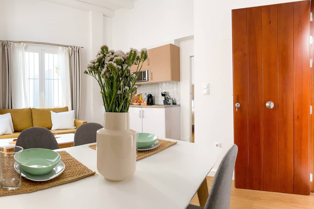 Een moderne eethoek met een witte tafel, groene kommen en een bloevas.