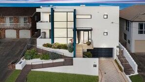 A modern two-story house with a flat roof, a garage, and a landscaped front yard. - Beach Bliss The Entrance North (The Entrance North)