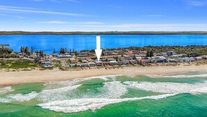 An aerial view of a coastal residential area with houses, a beach, and a large body of water. - Beach Bliss The Entrance North (The Entrance North)