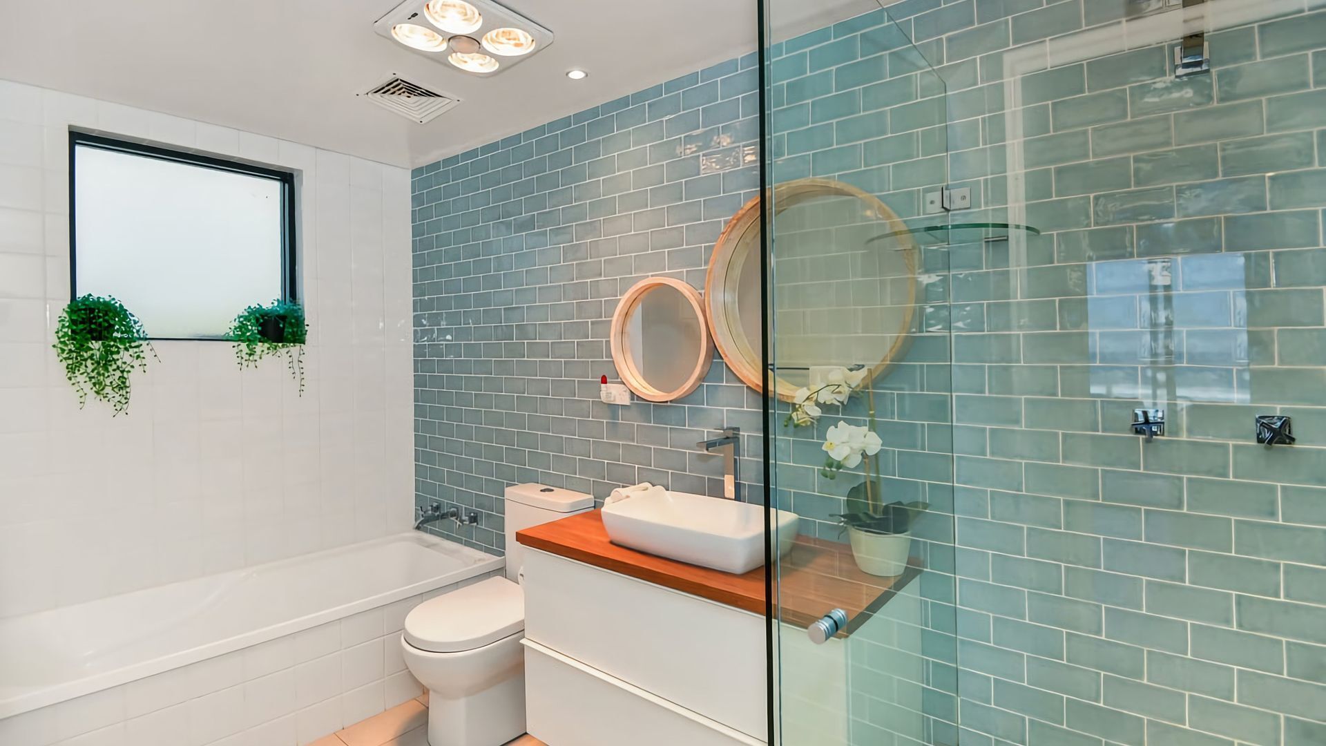 Un baño moderno con cabina de ducha de vidrio, bañera blanca y tocador de madera.