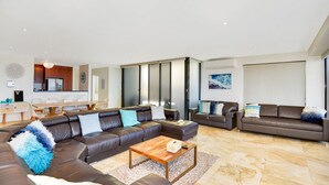 A modern living room with a sectional sofa, a coffee table, and a dining area with a table and chairs. - Beach Bliss The Entrance North (The Entrance North)