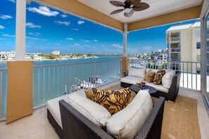 Ein Balkon mit Blick auf den Hafen und den Ozean, ausgestattet mit einer Couch und einem Couchtisch.