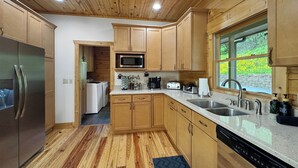 Una cucina moderna con mobili in legno, elettrodomestici in acciaio inossidabile e un'ampia finestra che si affaccia sul verde.