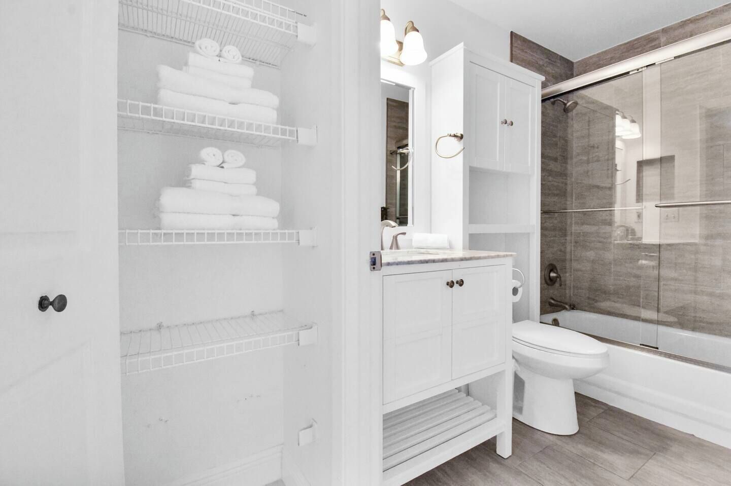 Une salle de bain moderne avec une douche à parois de verre, un meuble-lavabo blanc avec un miroir et un porte-serviettes intégré.