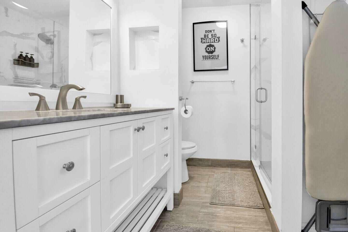 Une salle de bain moderne avec un meuble-lavabo blanc, un espace douche et des toilettes.