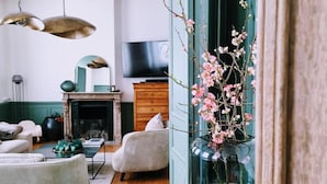 Una sala de estar con chimenea, televisor y un jarrón con flores.