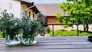 Una terraza de madera con dos jarrones de vidrio que contienen plantas verdes y flores moradas.
