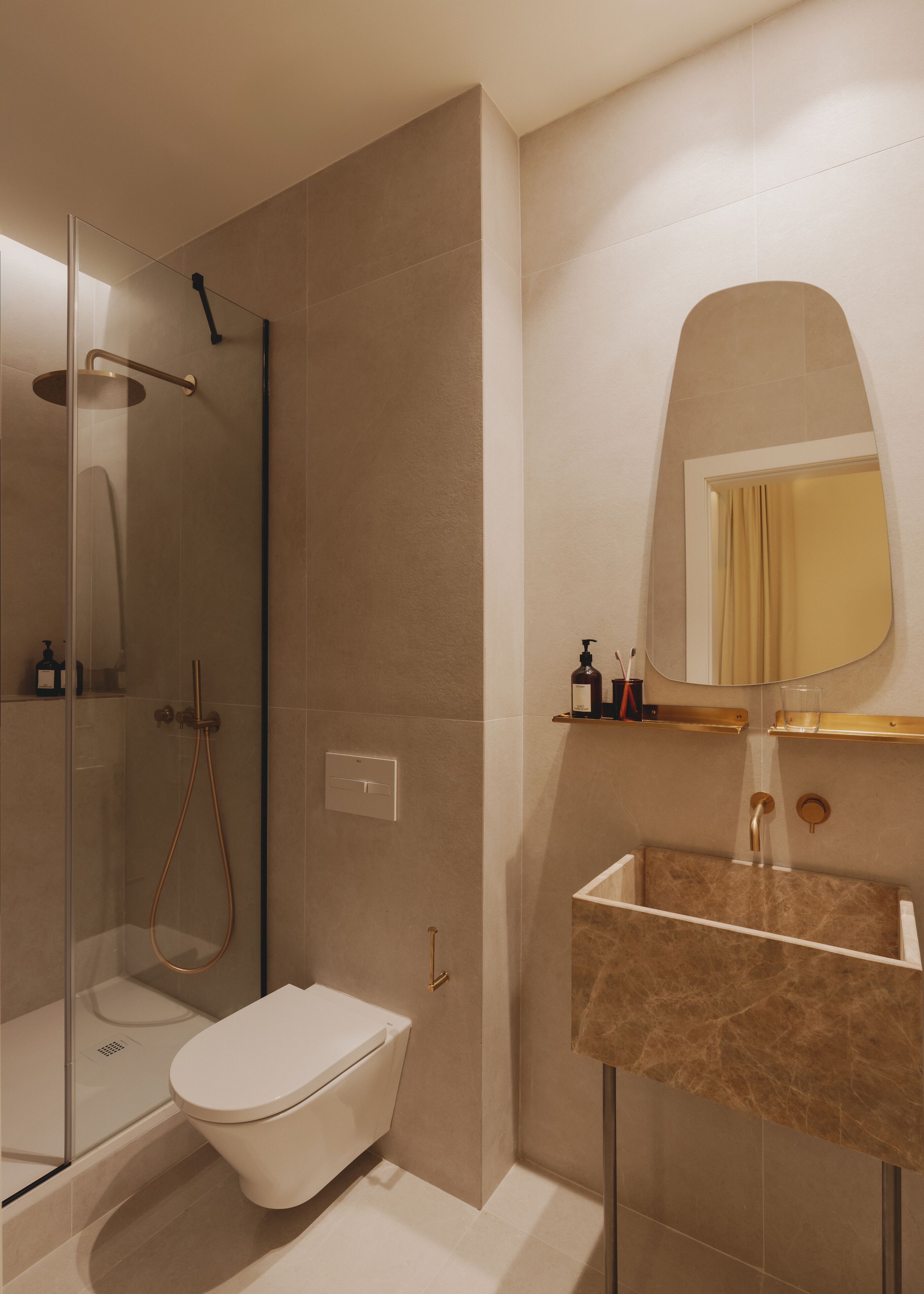 Een moderne badkamer met een douchecabine van glas, een toilet en een wastafel met een marmeren blad.