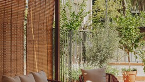 A patio area with wicker furniture, a glass table, and potted plants. - Casa Llimona Hotel Boutique (Barcelona)