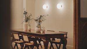 A dining area with a wooden table, six chairs, and two potted plants. - Casa Llimona Hotel Boutique (Barcelona)