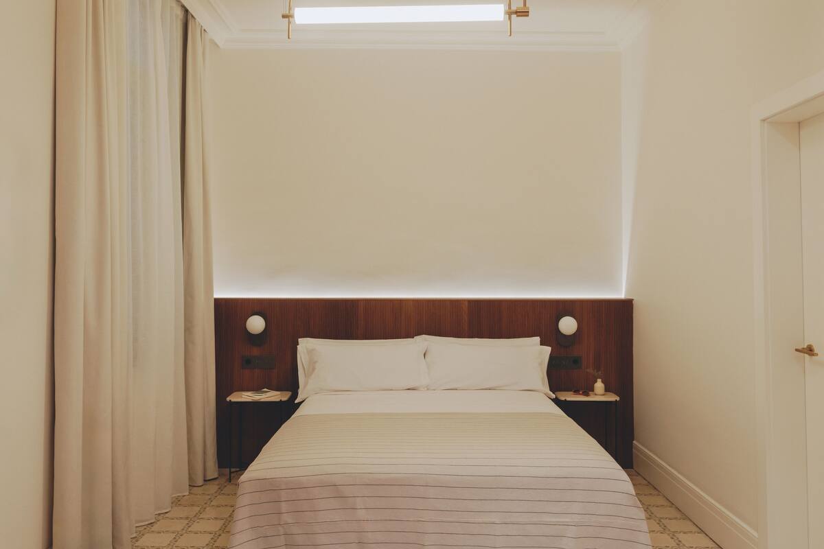A hotel room with a bed, nightstands, a wooden headboard, and a ceiling light fixture.