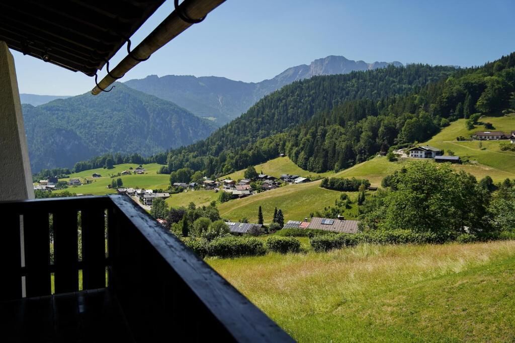 Ein malerischer Blick vom Balkon auf ein Dorf mit Häusern und Bergen im Hintergrund.