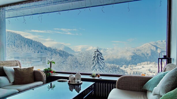 A cozy living room with a large window overlooking a snowy mountain landscape. - Villa Bello (Berchtesgaden)