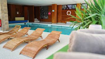 Un área de piscina con tumbonas de madera, un flotador y un extintor.