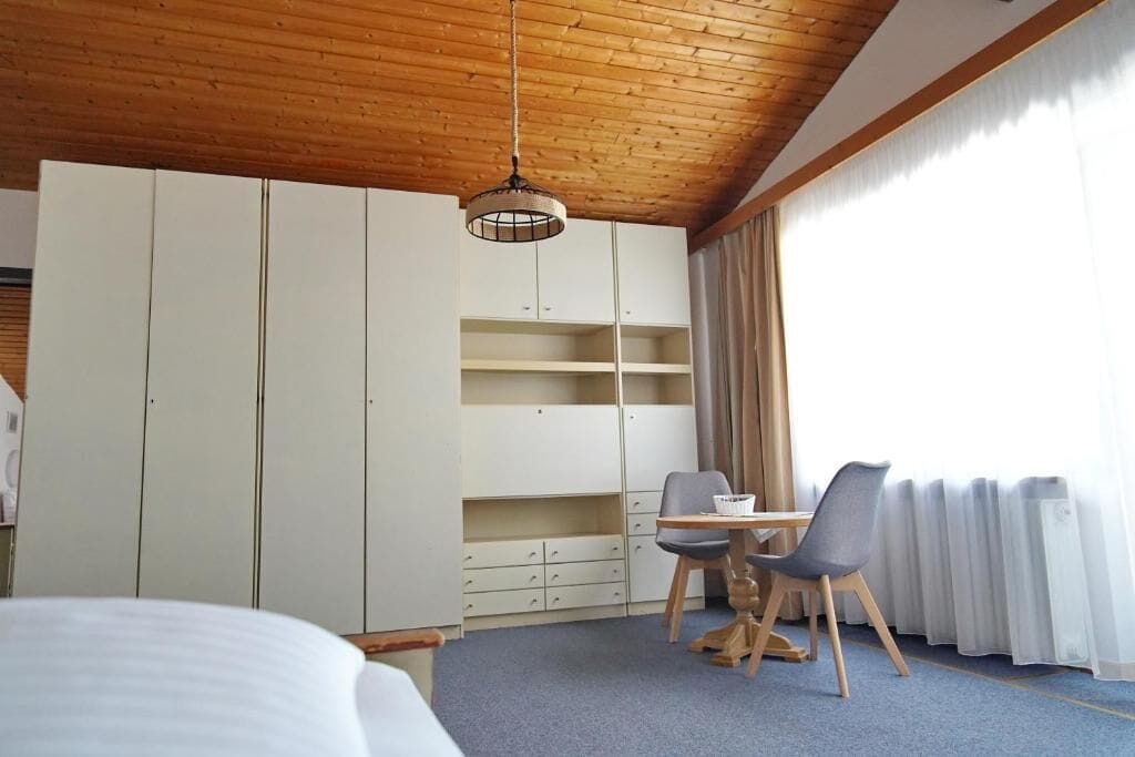 A bedroom with a bed, a desk with a chair, and a wardrobe.