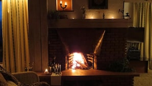 A cozy living room with a brick fireplace, a sofa, and a table with candles. - Villa Bello (Berchtesgaden)
