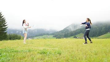 Two people playing with a frisbee on a grassy field with a mountainous backdrop.