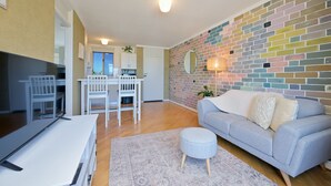 Ein modernes Wohnzimmer mit einem grauen Sofa, einem kleinen Hocker und einem Essbereich mit weißer Möbel.