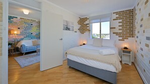 Ein Schlafzimmer mit einem Bett, Nachttischen, einem Fenster und Blick ins Freie.