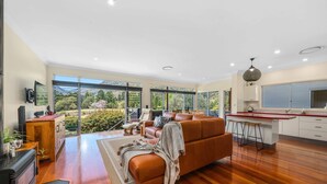 A spacious living area with a large sofa, a kitchen with a red countertop, and a view of the outdoors.