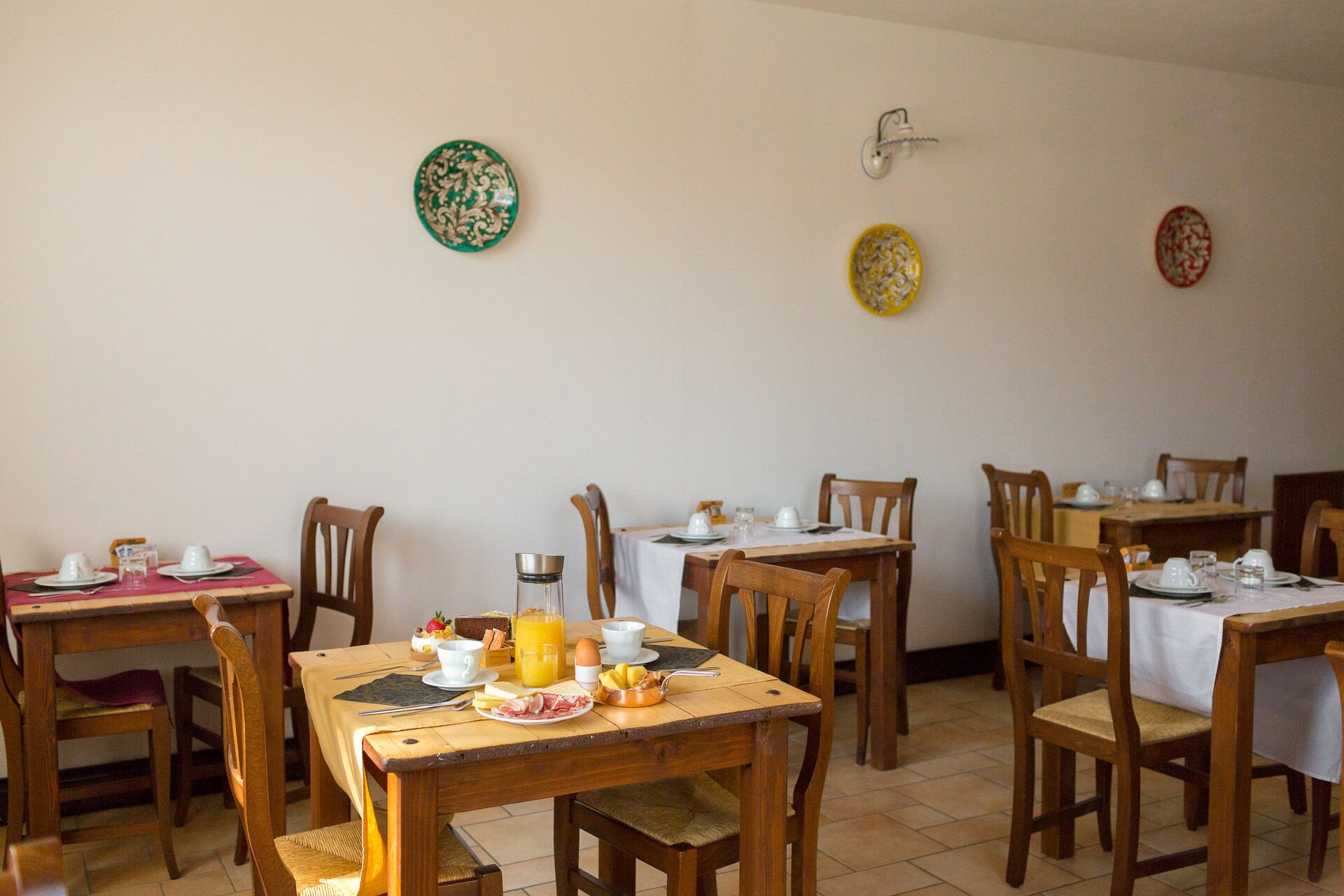 A dining area with multiple tables set for breakfast, each with plates, cups, and cutlery.