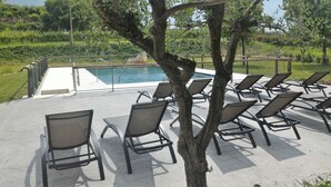 Un área junto a la piscina con sillones de descanso y una pileta.