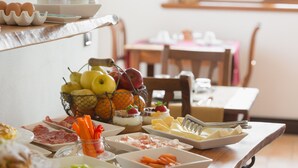 Un bufé de desayuno con diversas opciones de comida y una cesta de frutas.
