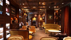 A classic interior with wooden paneling, leather armchairs, and a central round table. - TLV Port Boutique Residence (Tel Aviv)