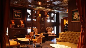 A warmly lit room with wooden paneling, leather armchairs, a tufted sofa, and a fireplace. - TLV Port Boutique Residence (Tel Aviv)