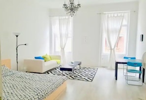 Relax in a stylish room with a large bed, sofa, and desk, surrounded by sheer curtains and a patterned rug.