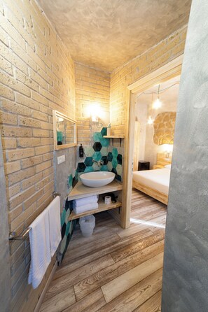 Un baño con suelo de madera, un lavabo blanco, un espejo y un perchero para toallas.