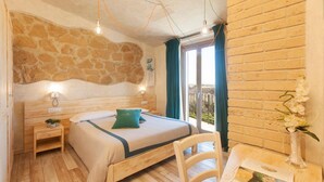 Una camera da letto con parete in pietra, letto di legno, comodini, una sedia e vista sull'esterno.