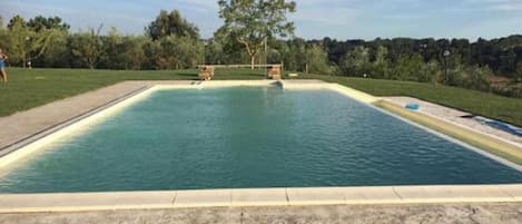 A rectangular swimming pool with a tiled deck in front.