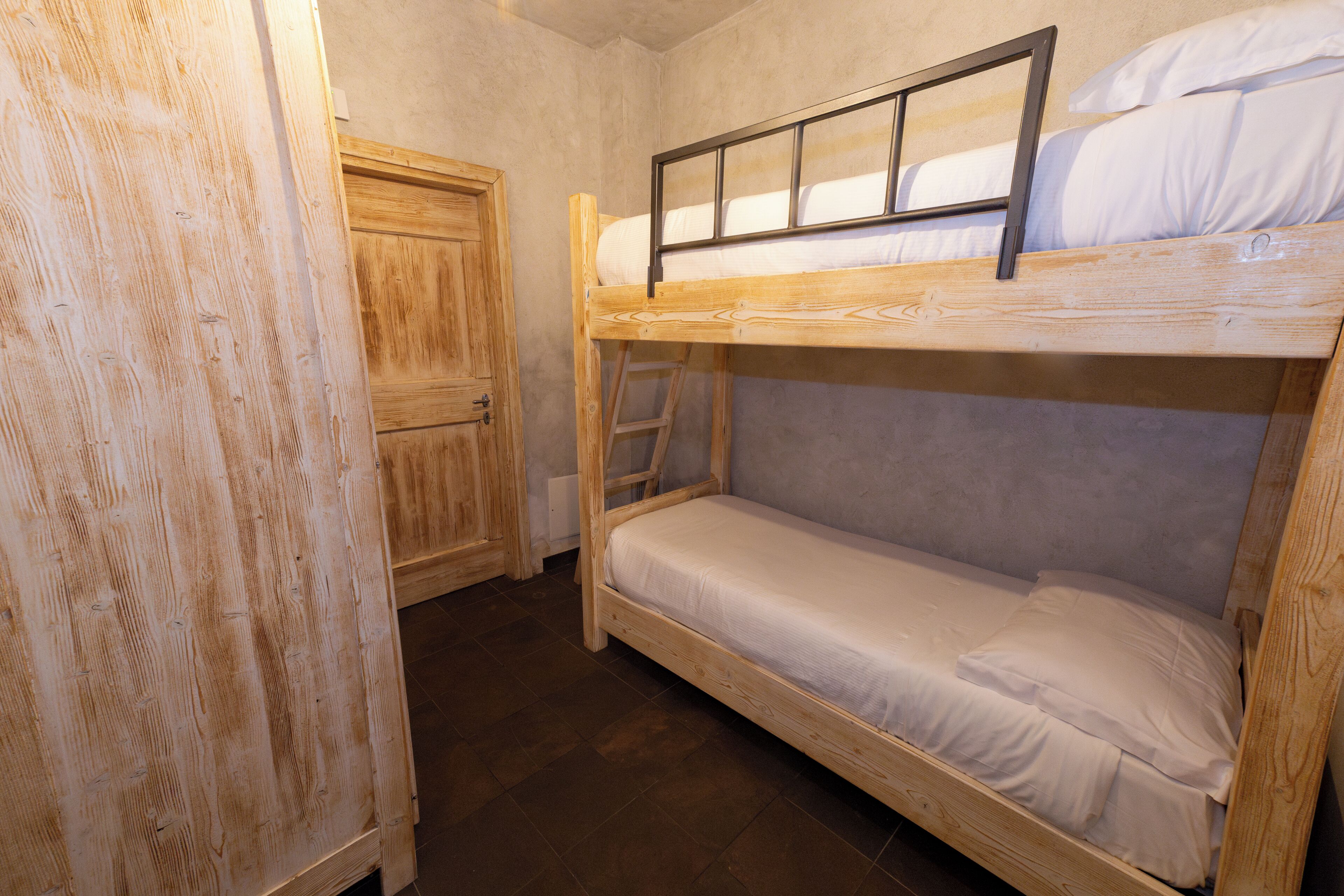 A bunk bed room with a wooden wardrobe and a door.