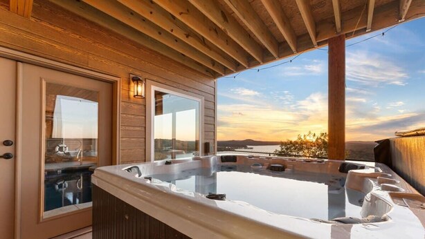 Un espace avec un bain à remous, doté d’un plafond en bois et de grandes fenêtres offrant une vue panoramique.