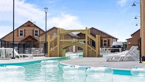 Un espace piscine agrémenté d’un pont en bois, de chaises longues et d’un ciel dégagé.
