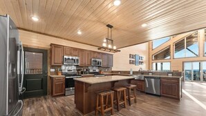 Une cuisine spacieuse, dotée de meubles en bois, d’appareils électroménagers en acier inoxydable et d’un grand îlot central avec des tabourets.