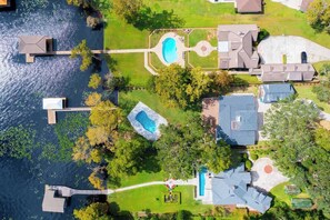 Vista aérea de uma área residencial com piscina, cais e várias casas.