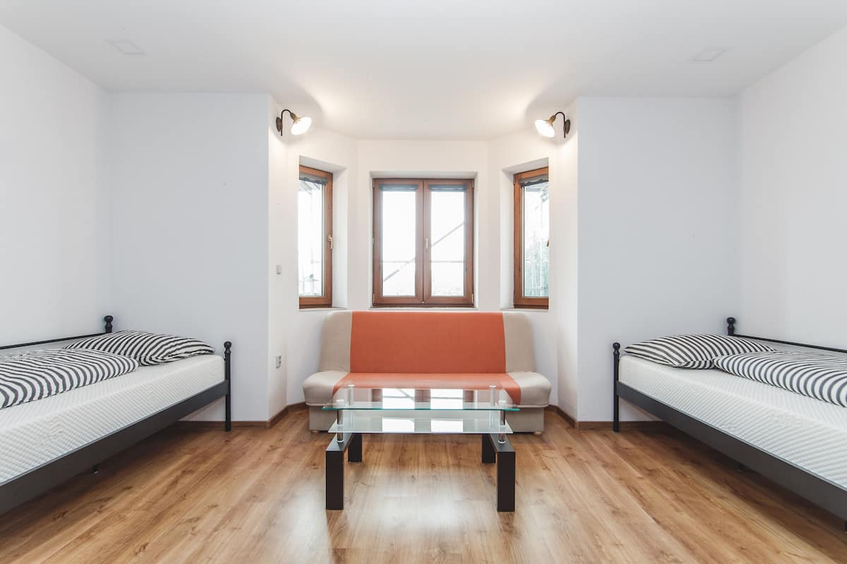 A room with two single beds, a sofa, and a glass-top table.