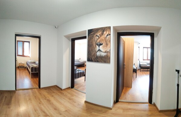 A hallway with wooden flooring, a bed with a headboard, and a large lion painting on the wall. - Villa u Arény (Ostrava)