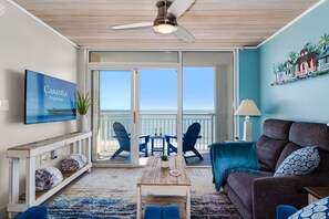 Enjoy ocean views from the comfort of this living room, featuring a sofa, chairs, and a TV.