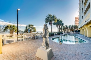 Relax by the pool surrounded by a classical statue and lush palm trees.