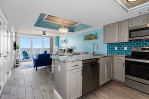 Enjoy cooking in this well-equipped kitchen with a central island, dishwasher, and sink, adjacent to a balcony with a view.
