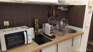 Een kleine keuken met een magnetron, broodrooster en spoelbak.