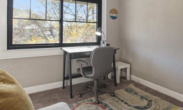 A small office with a desk, chair, and a window with a view of trees.