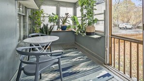 Ein Wintergarten mit Tisch und Stühlen, großen Fenstern und verschiedenen Topfpflanzen.