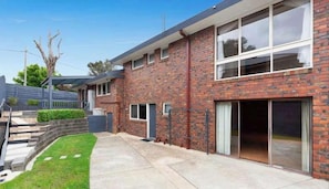 Een modern huis van baksteen met grote ramen, een overdekte patio en een verzorgd gazon.